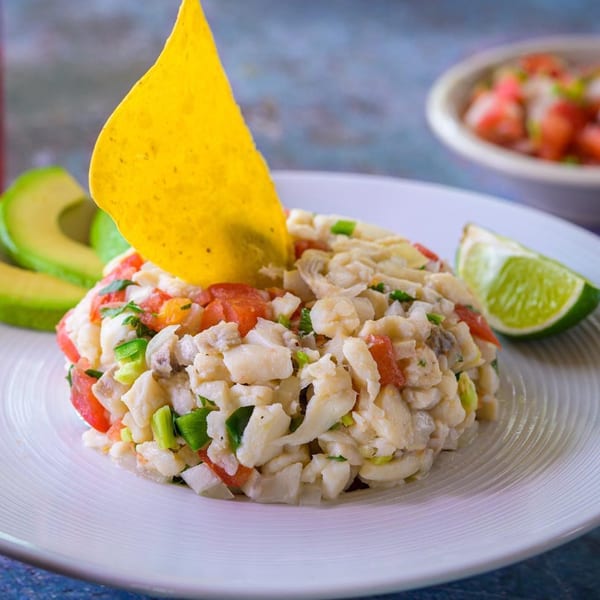 Cantina Caramba!'s ceviche with white fish, tomatoes, green onions, a tortilla chip, avocado, and lime.