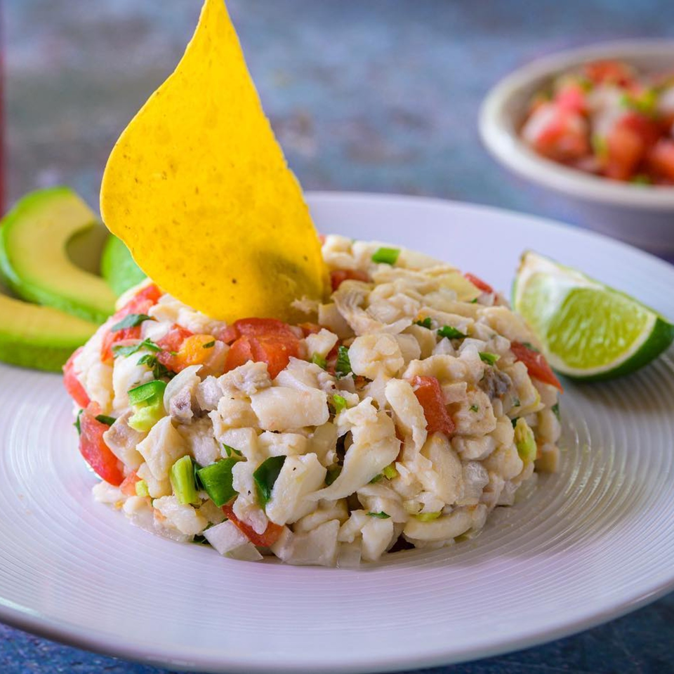 Cantina Caramba!'s ceviche with white fish, tomatoes, green onions, a tortilla chip, avocado, and lime.