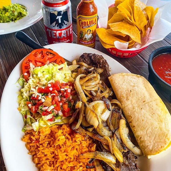 Cantina Caramba!'s carne asada plate with rice, beans, salad, tortilla, chips, salsa, and drinks.